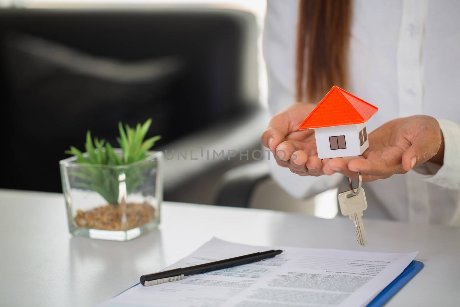 Orange roof house.Holding key and houses .House in the hands of businessmen Or sales representative.Agents are giving home and home keys to customers.Home buying and home insurance concept.