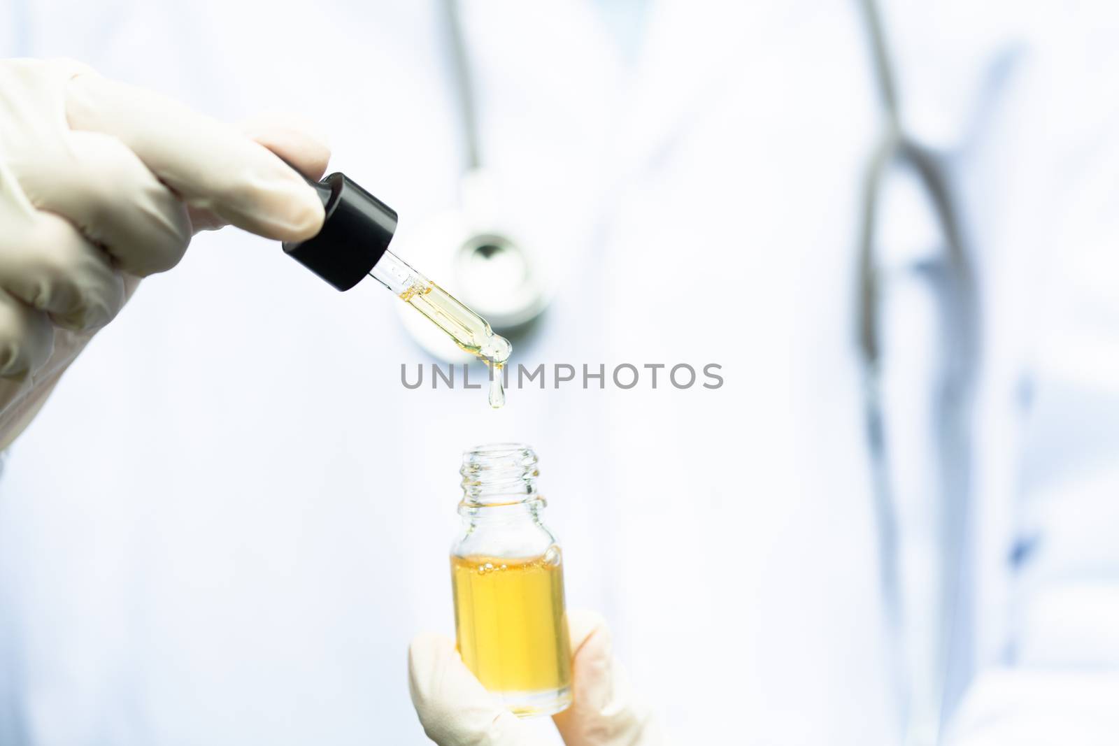 Glass bottle handle, CBD hemp oil. Doctors or researchers hold a bottle of hemp oil. Background with medical stethoscope.medical marijuana concept, CBD cannabis OIL. hemp product, close up