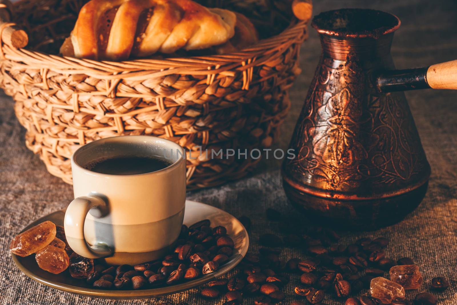 Cup of turkish coffee with cezve and basket of cakes on background