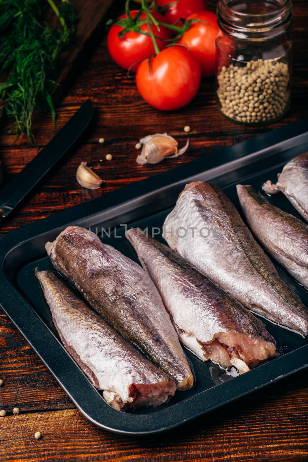 Hake carcasses on baking sheet with vegetables and spices