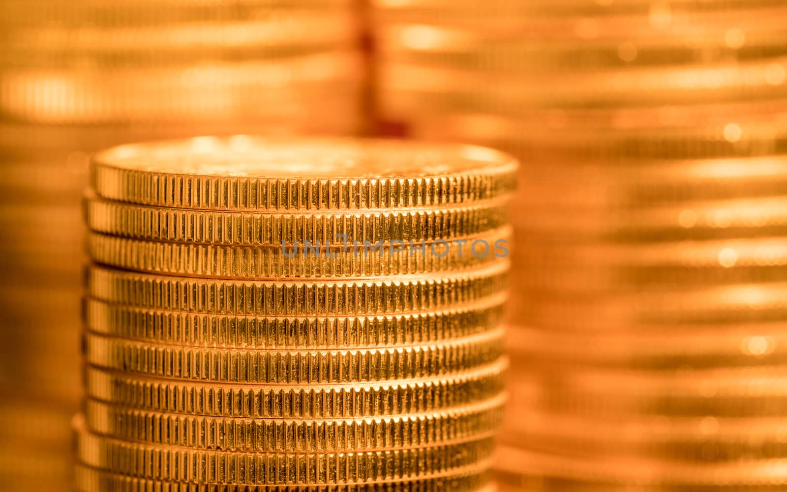 Focus on a stack of gold coins with other coin stacked in the background out of focus