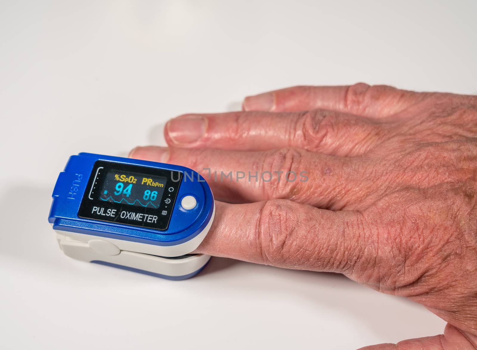 Senior man using a pulse oximeter on finger to test blood oxygen level by steheap