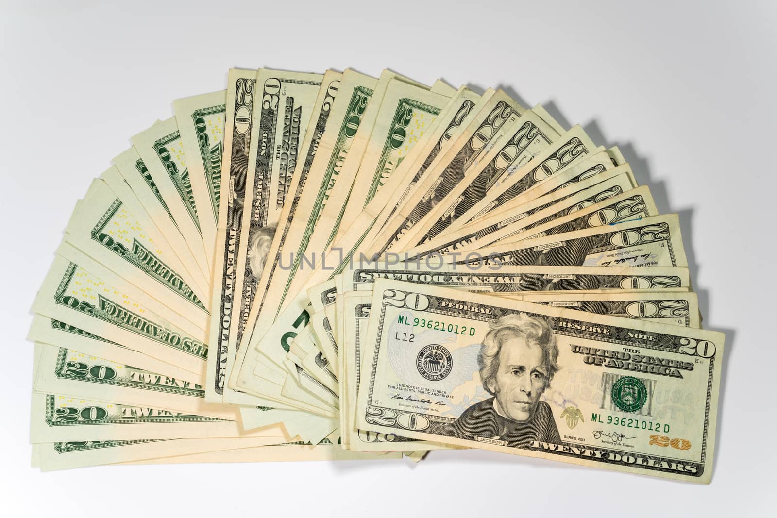 Thousands of US dollars laid out in a fan shape with 20 dollar bills against a white background