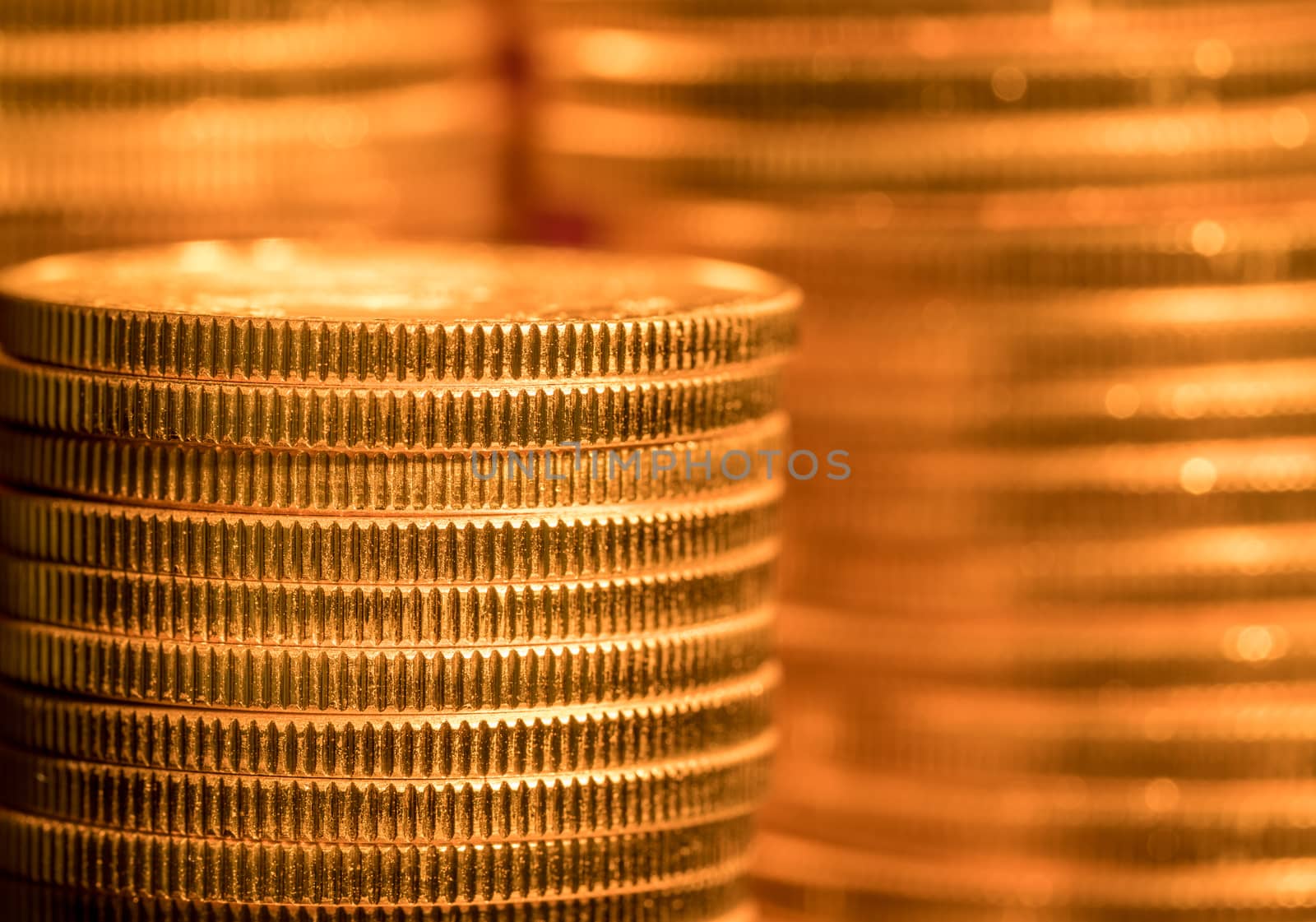 Focus on a stack of gold coins with other coin stacked in the background out of focus