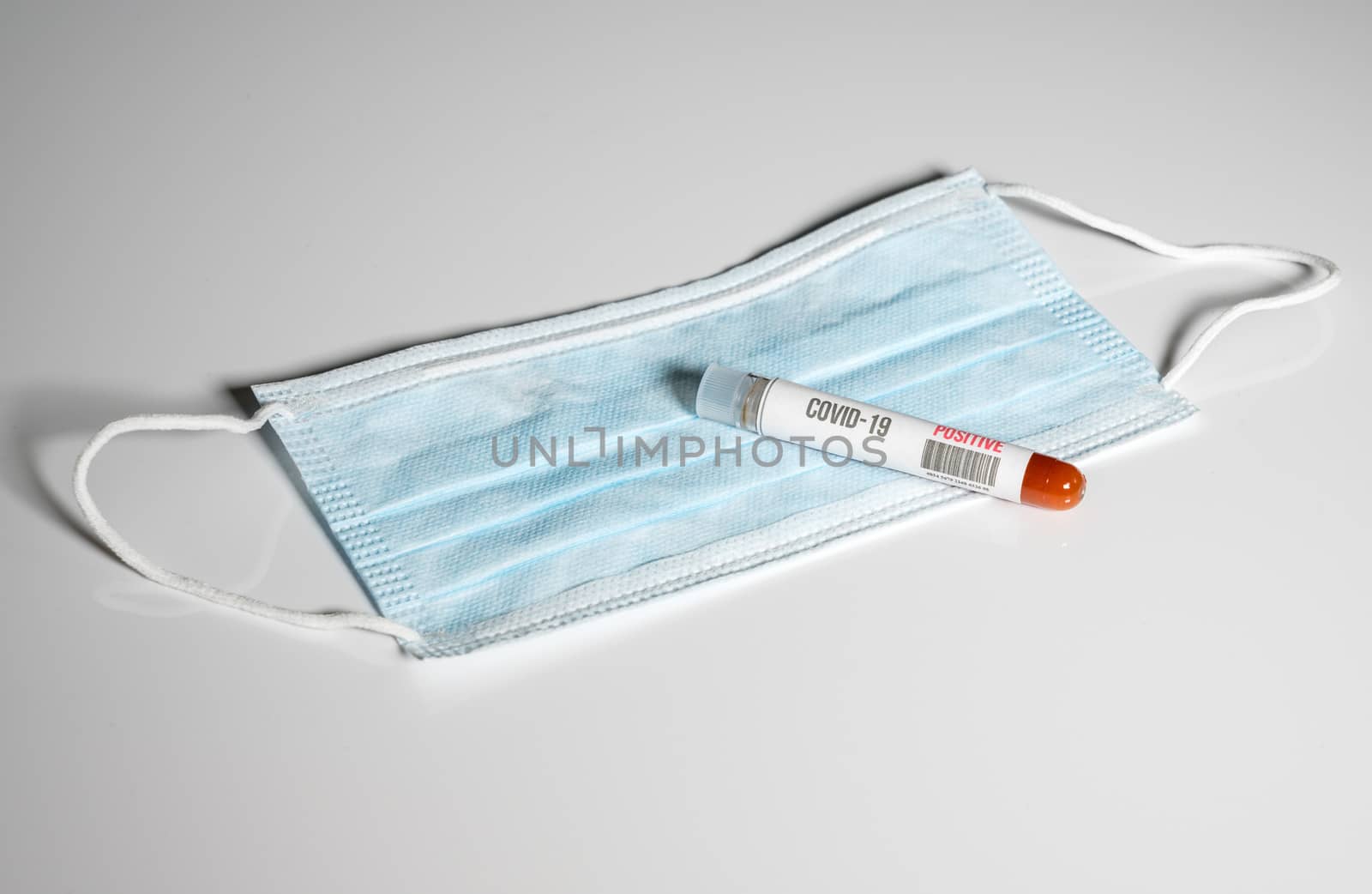 Positive blood test for Coronavirus laying on doctor surgical mask to show danger to front line medical workers
