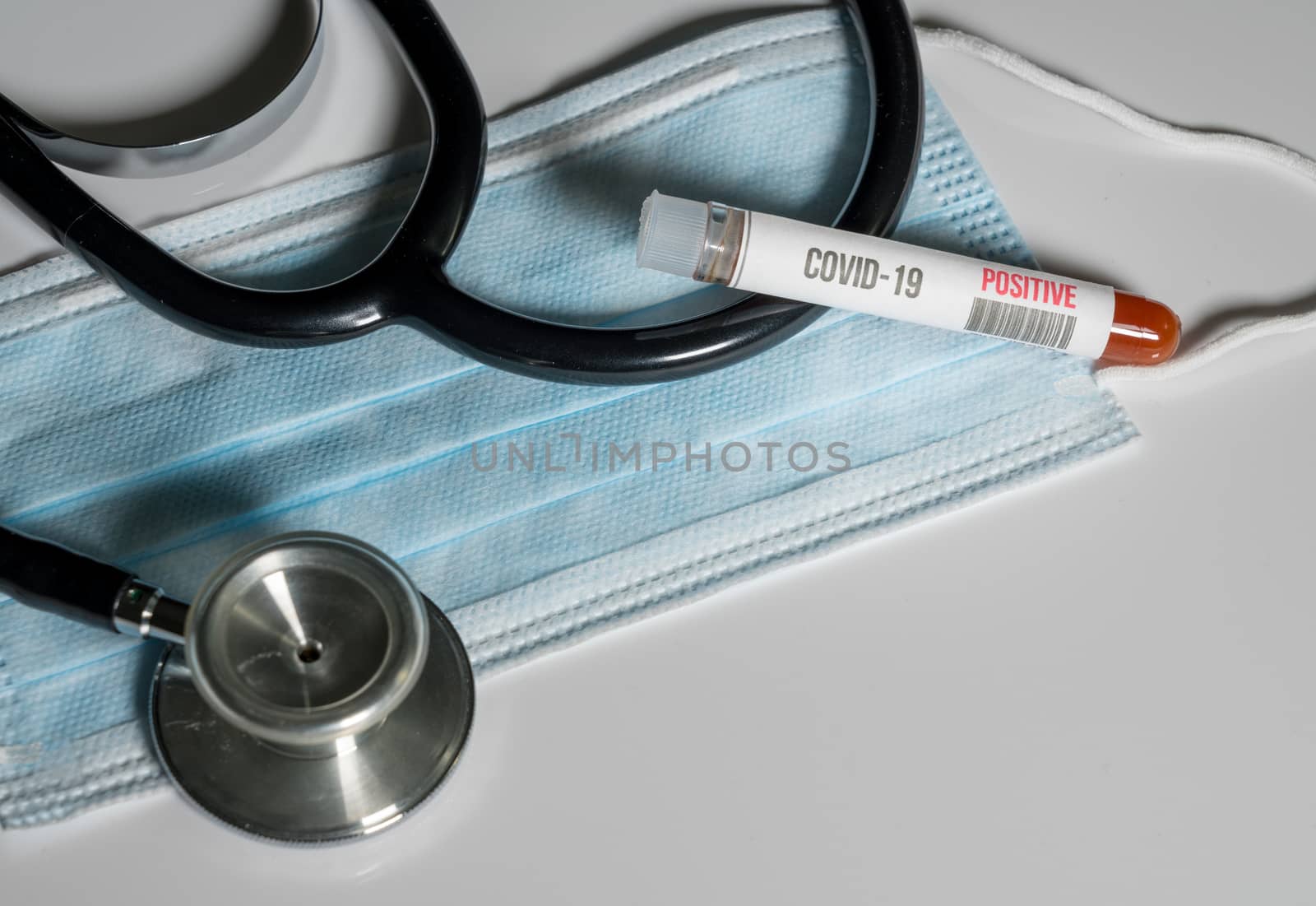 Positive blood test for Coronavirus laying on doctor surgical mask with stethoscope to show danger to front line medical workers