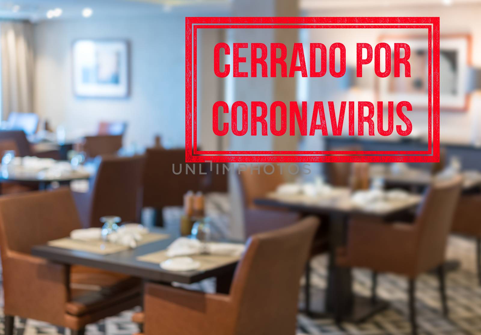 Modern restaurant with tables closed and sign in spanish saying Closed due to Coronavirus by steheap