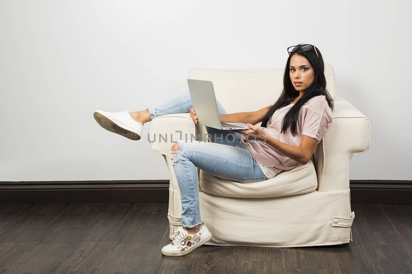 Young woman working on a laptop, sitting on a white couch