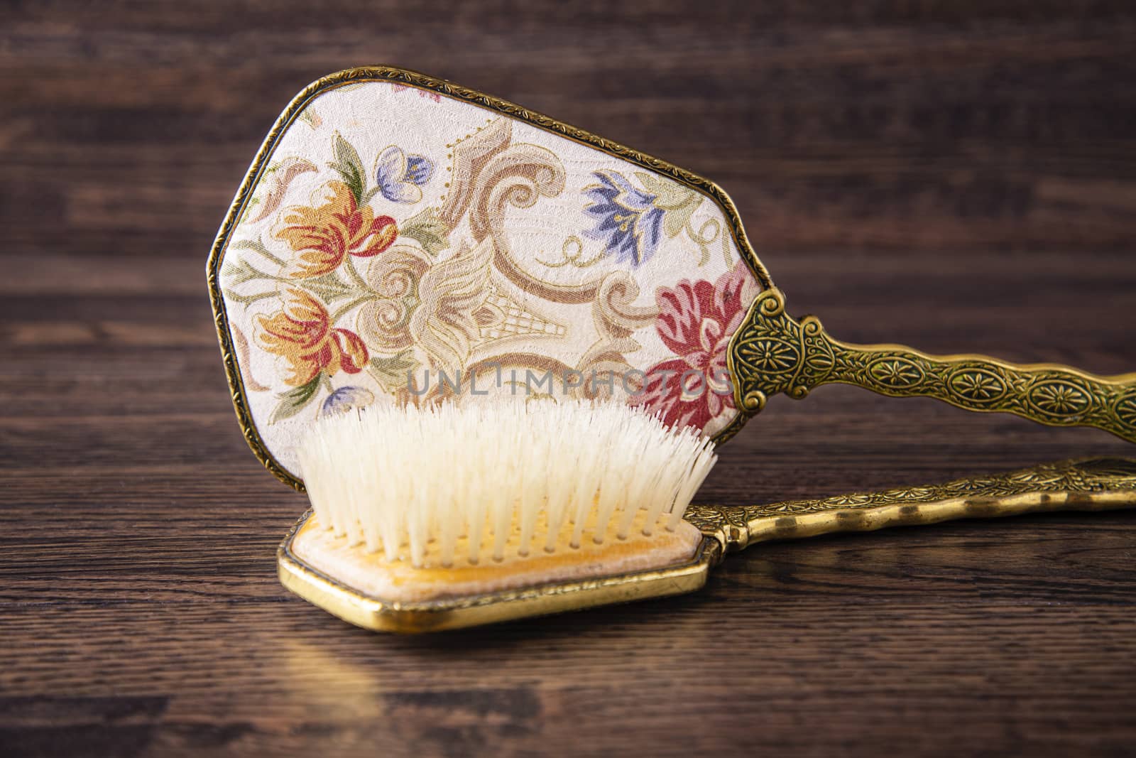 Vintage antique hand mirror and hair brush against dark wood background