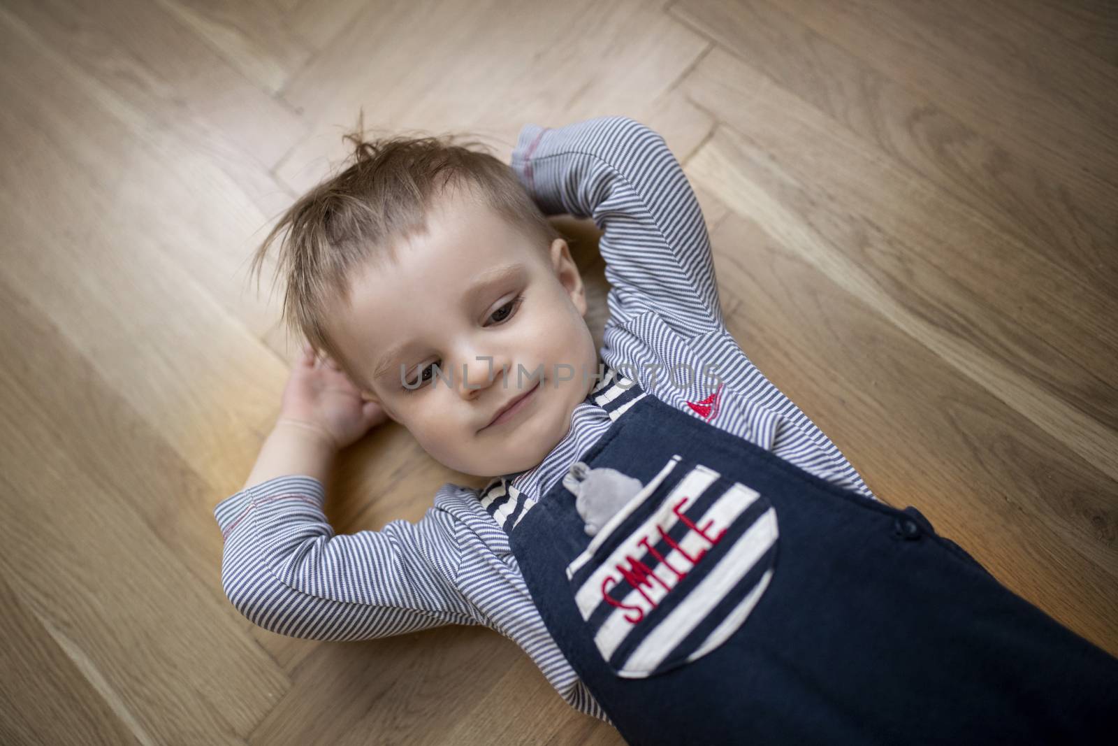 Little boy lying on floor with hands behind his head