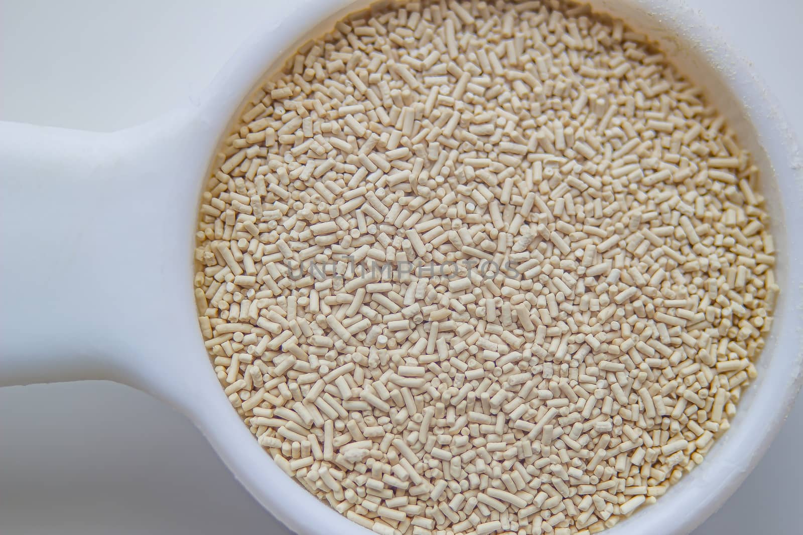 A top view close up of a measurement baking spoons with yeast on a white background