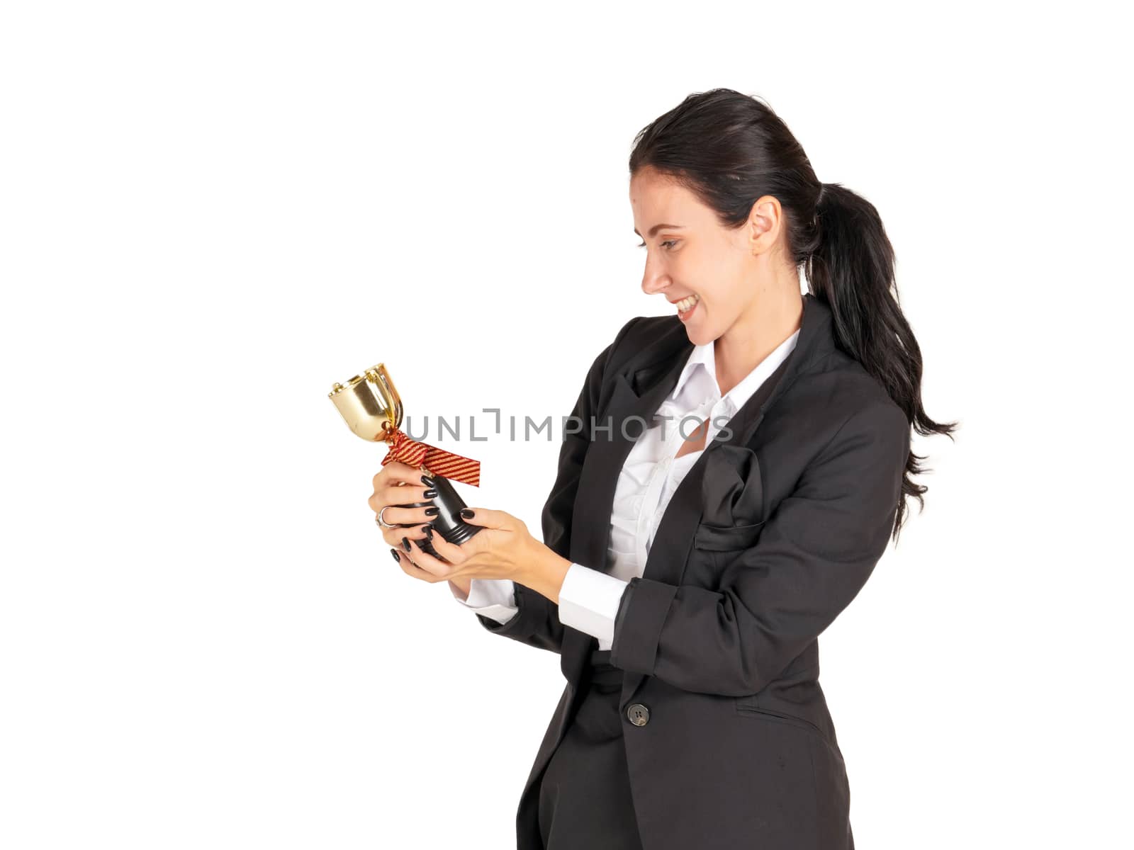 A businesswoman in a black suit with a smile looking at the trophy received from the work done proudly. Portrait on white background with studio light.
