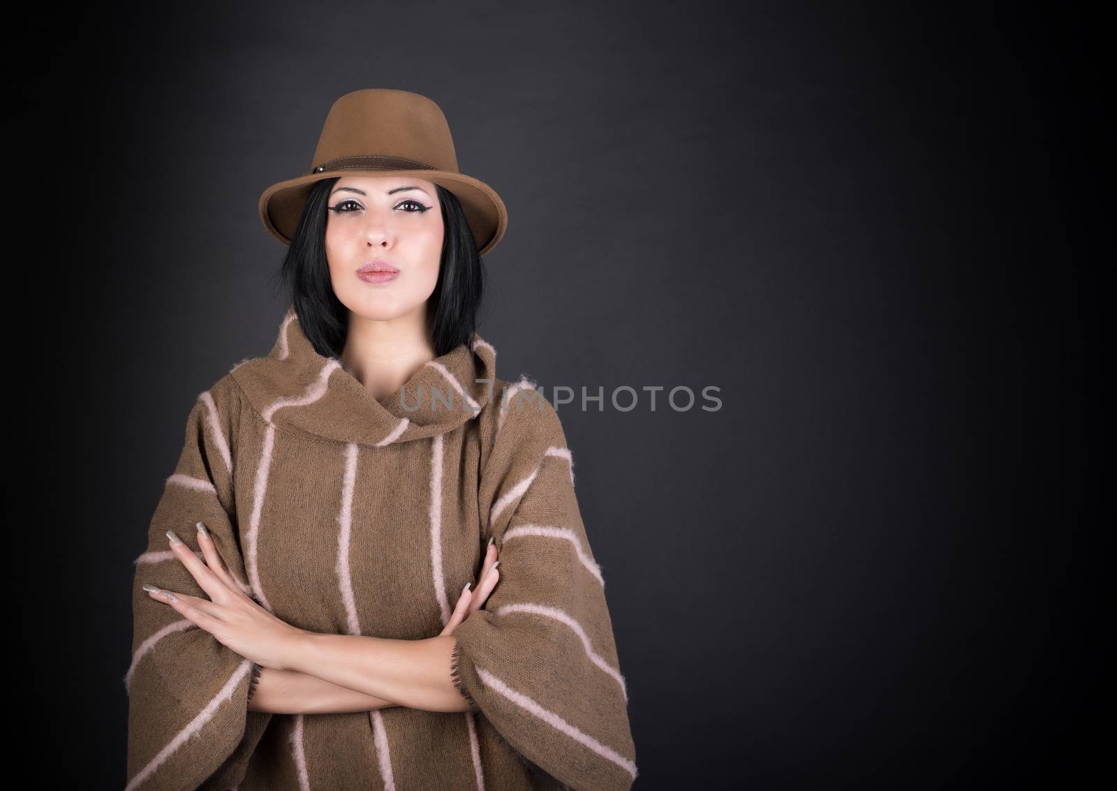 Fashion beautiful woman in country outfit and hat looking in camera on black background
