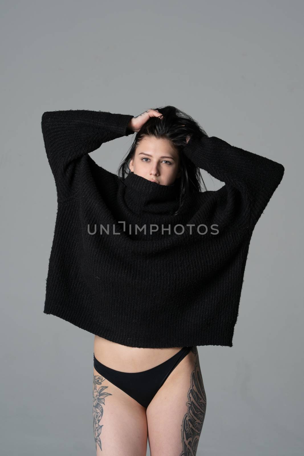 young beautiful girl pose in a black sweater in the studio