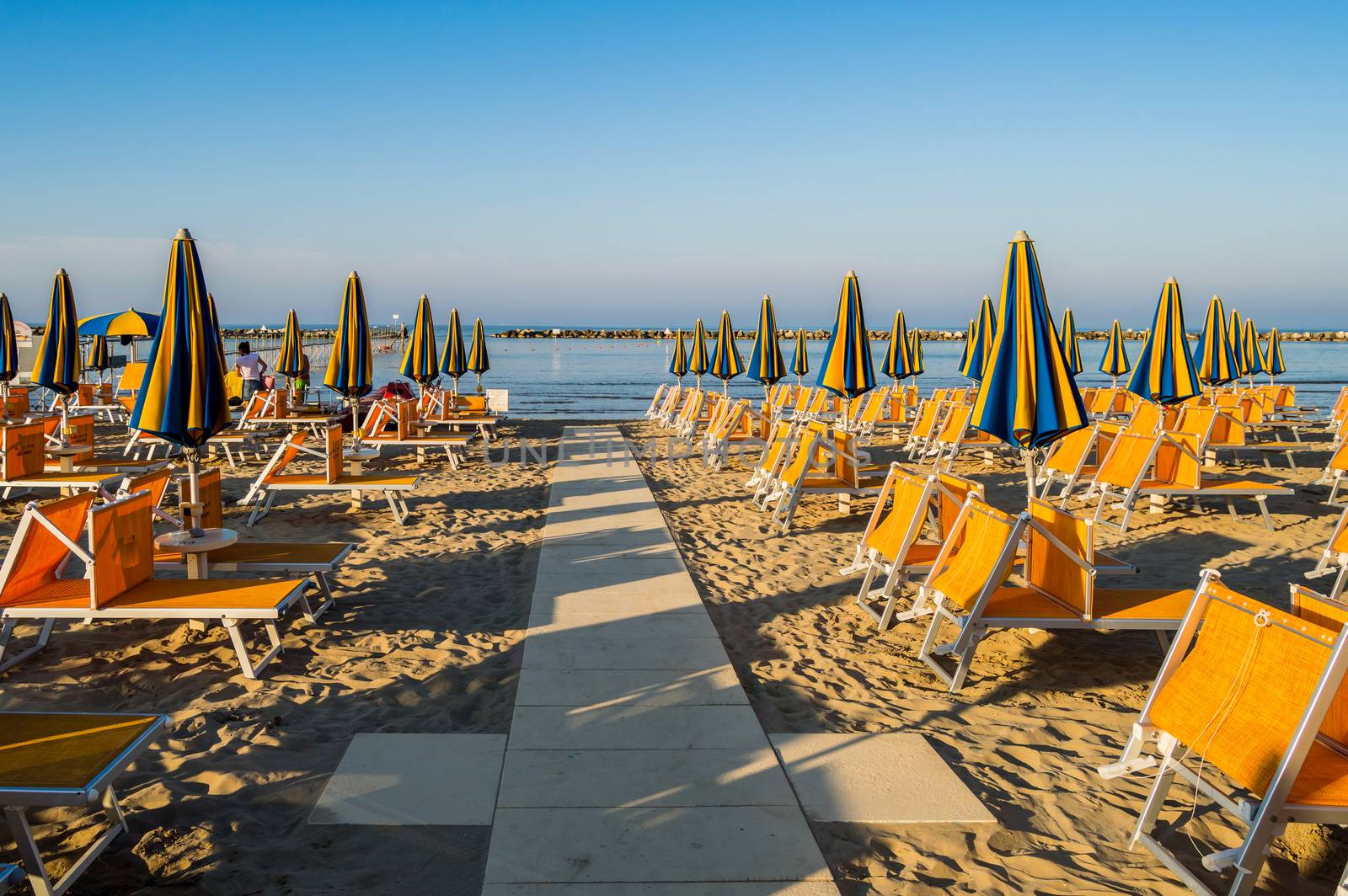 Rows of orange umbrellas and deckchairs on the beach of Igea Marina near Rimini