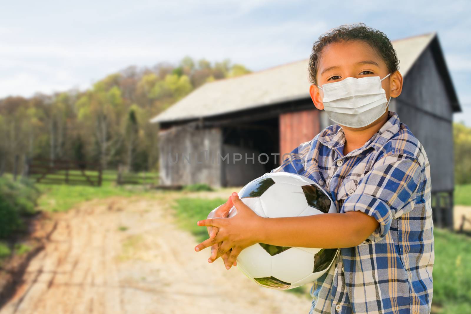 Mixed Race Hispanic and African American Boy Holding Soccer Ball Wearing Face Mask Outdoors. by Feverpitched