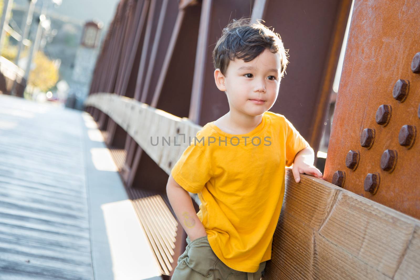 Mixed Race Chinese and Caucasian Boy Playing Alone on Bridge.