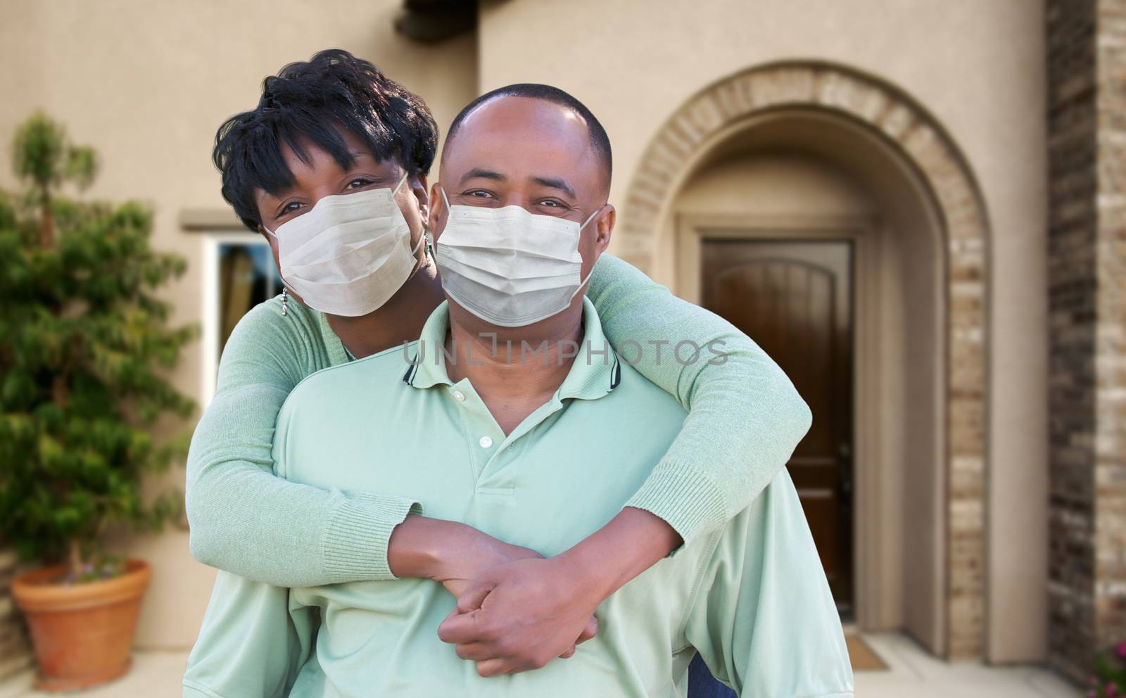 Loving African American Couple Hugging Wearing Medical Face Masks In Front of House.