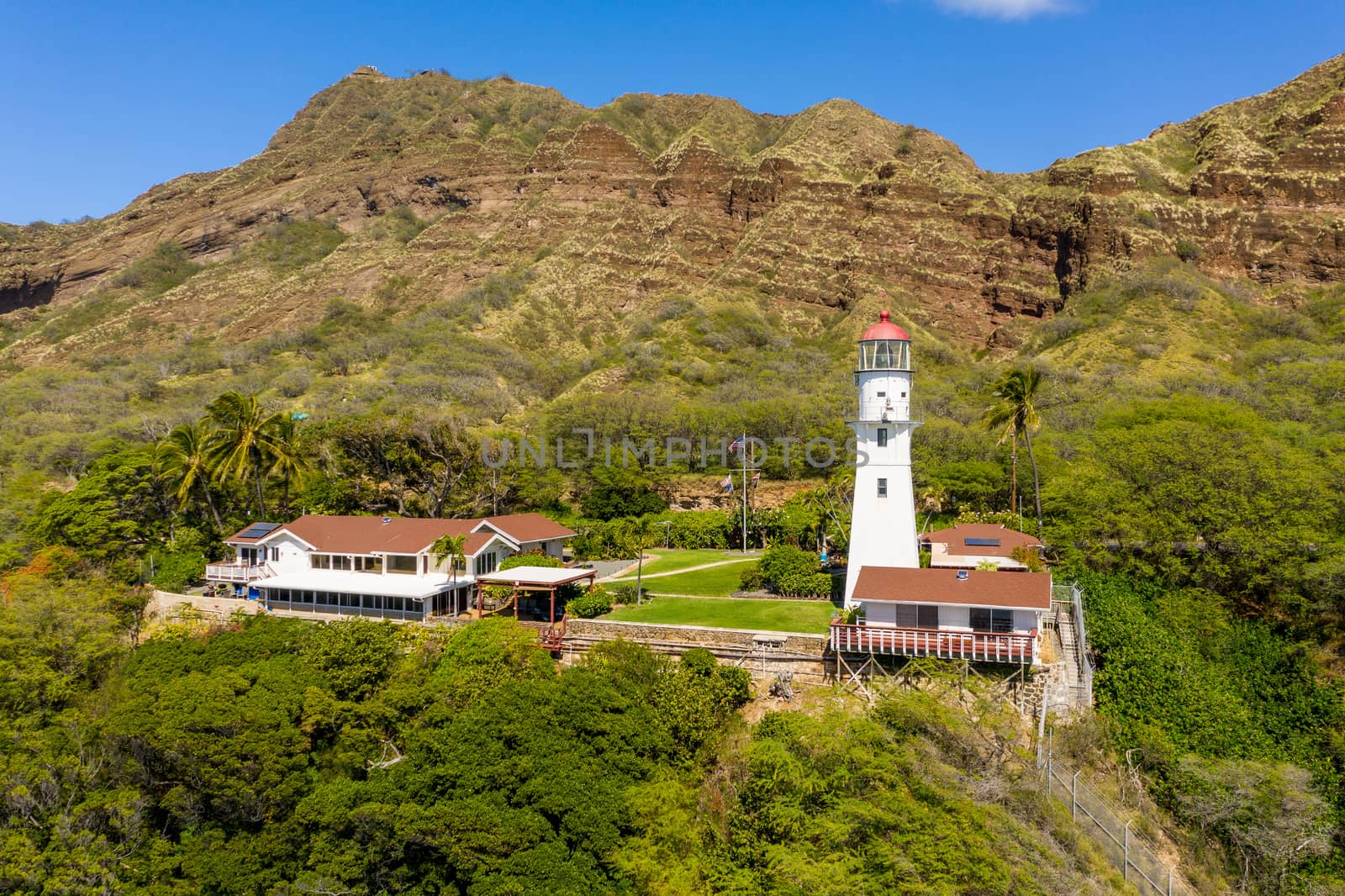 Aerial view of old white lighthouse under Diamond Head on Oahu from the ocean