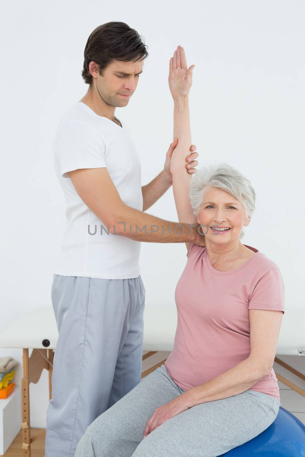 Senior woman sitting on yoga ball while working with a physical therapist