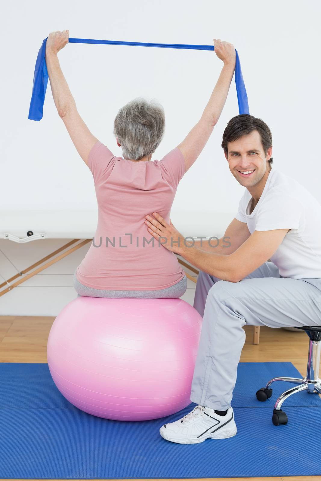 Senior woman sitting on yoga ball while working with a physical therapist