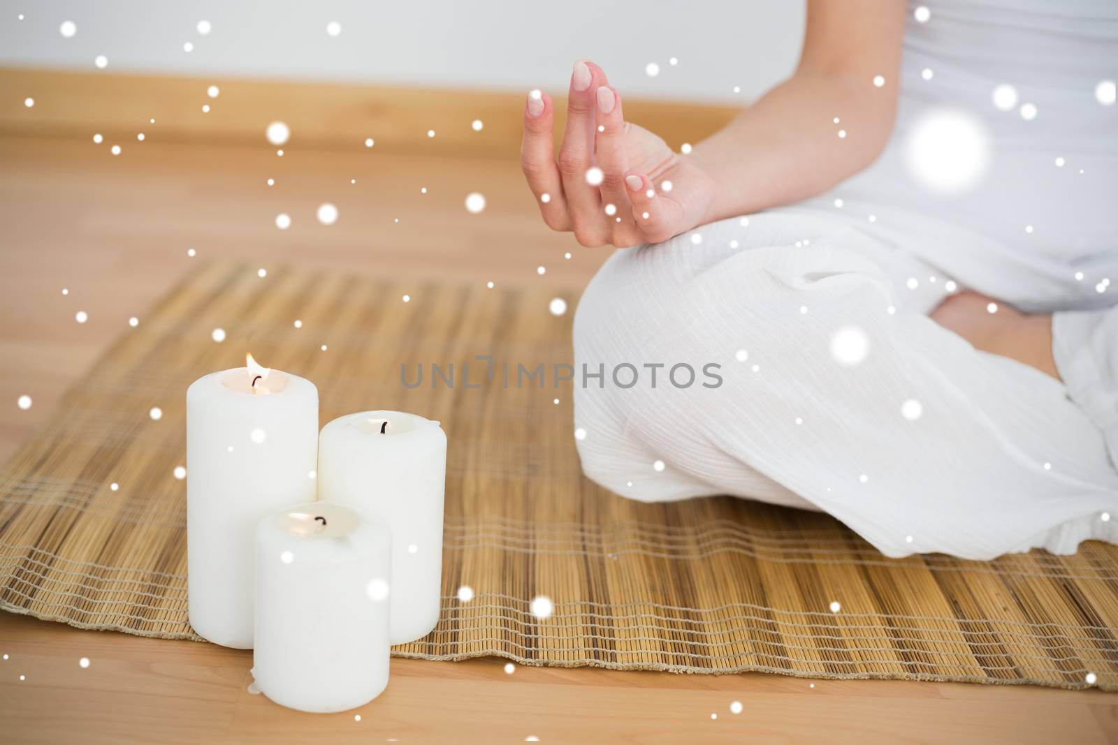 Woman sitting in lotus pose beside white candles by Wavebreakmedia