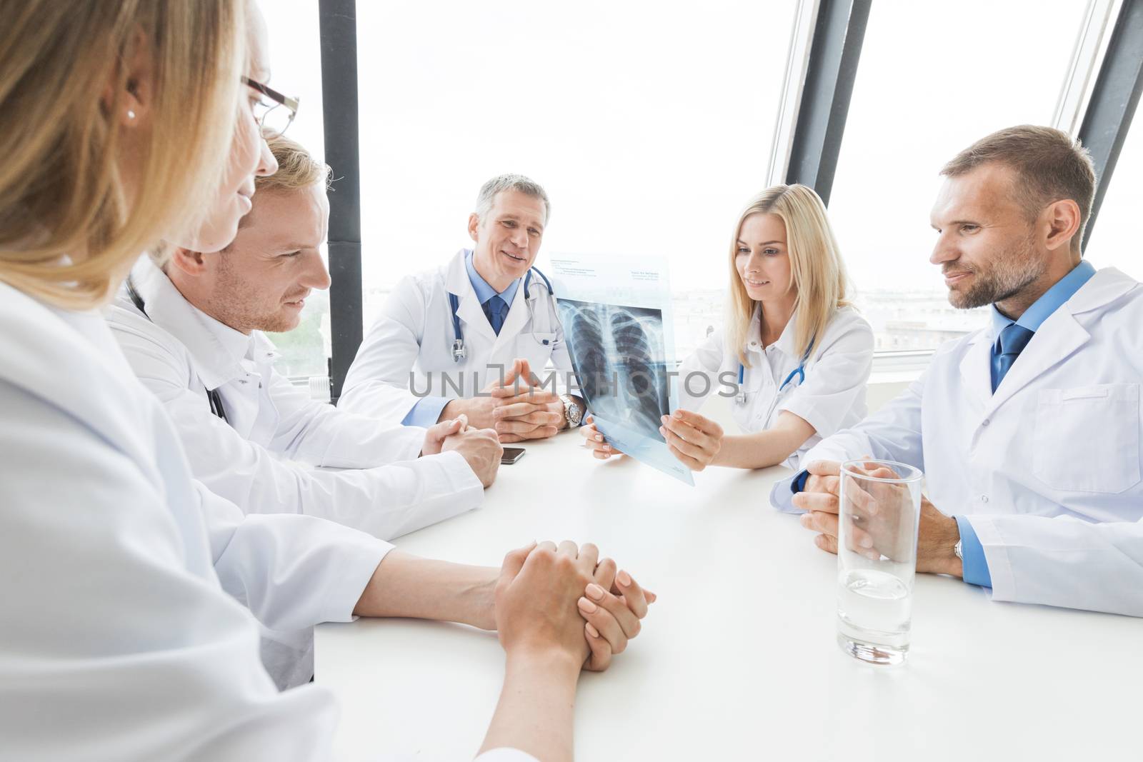 Team of experts doctors examining X-ray report on hospital office meeting