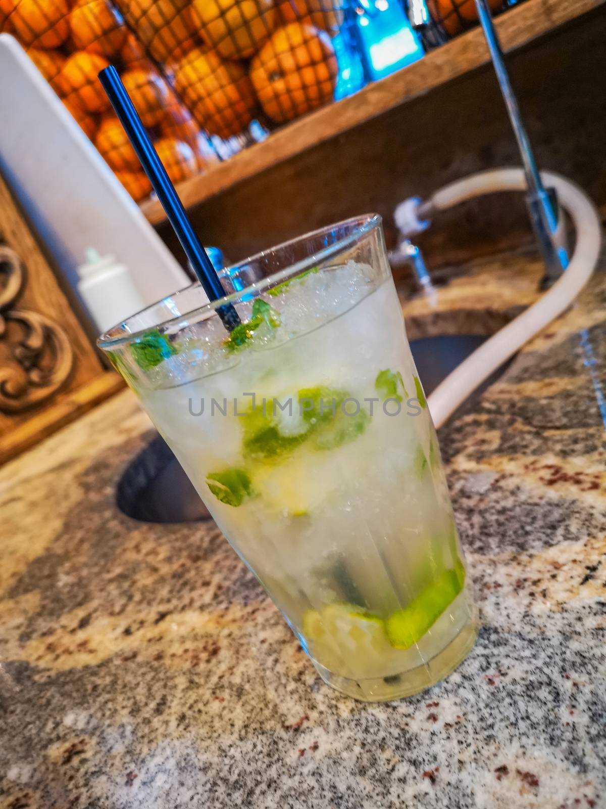 Mojito drink in high glass filled with crushed ice behind bar