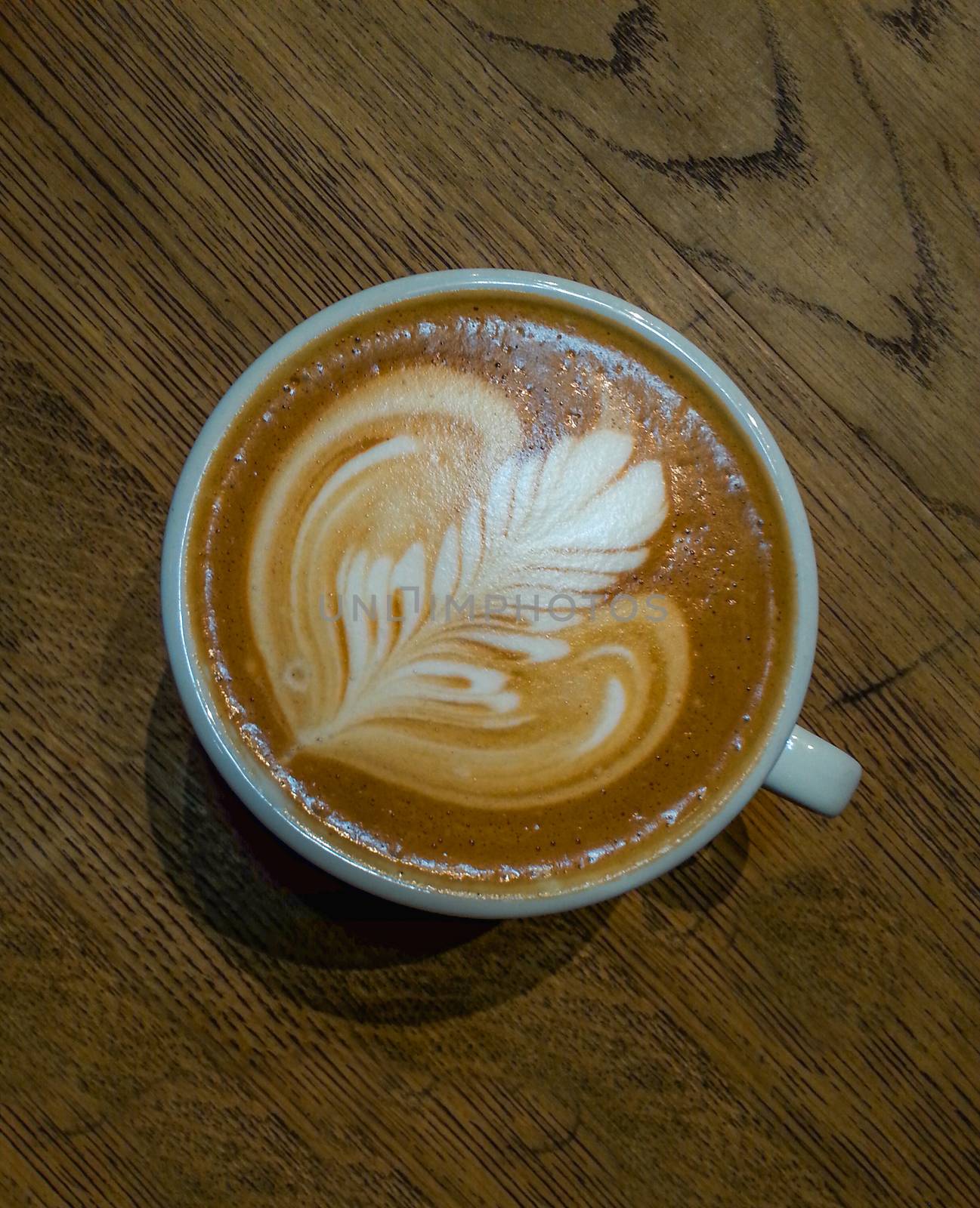 Rosette latte art on cafe latte on wooden table