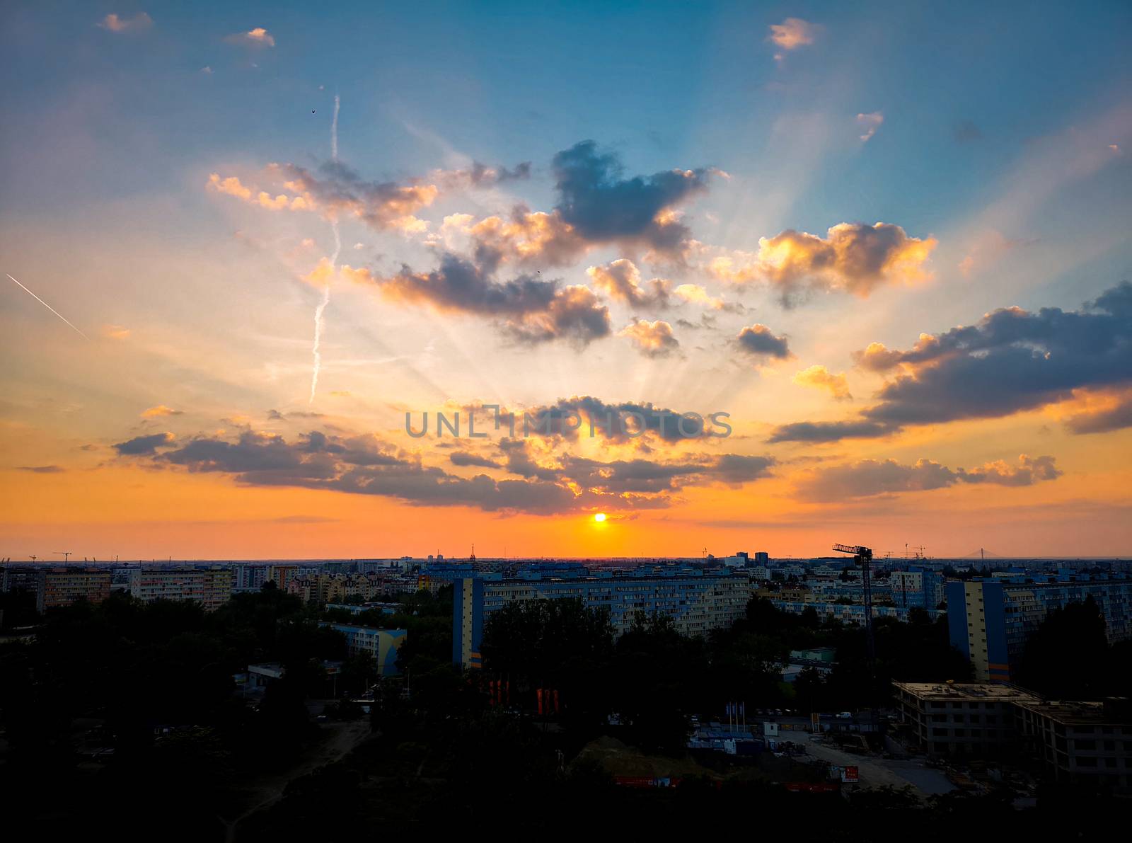 Cloudy gold sunset over city apartment buildings by Wierzchu