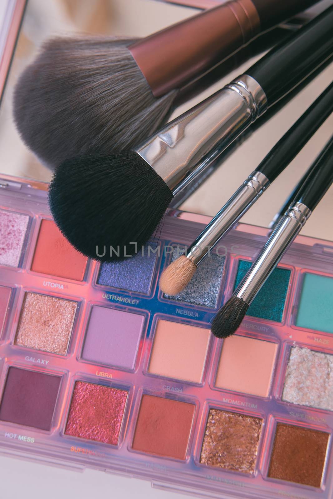 Makeup brushes and color palete on white background