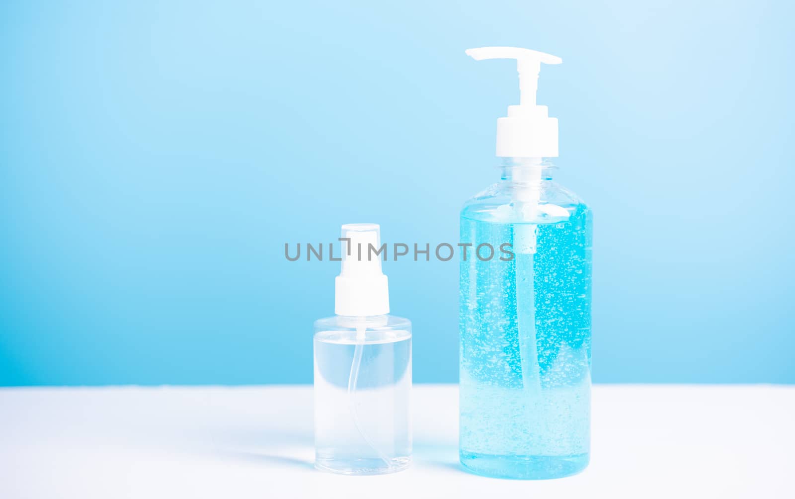 Plastic dispenser sanitizer alcohol gel pump and spray bottle for washing hand hygiene prevention of coronavirus virus studio shot on blue background