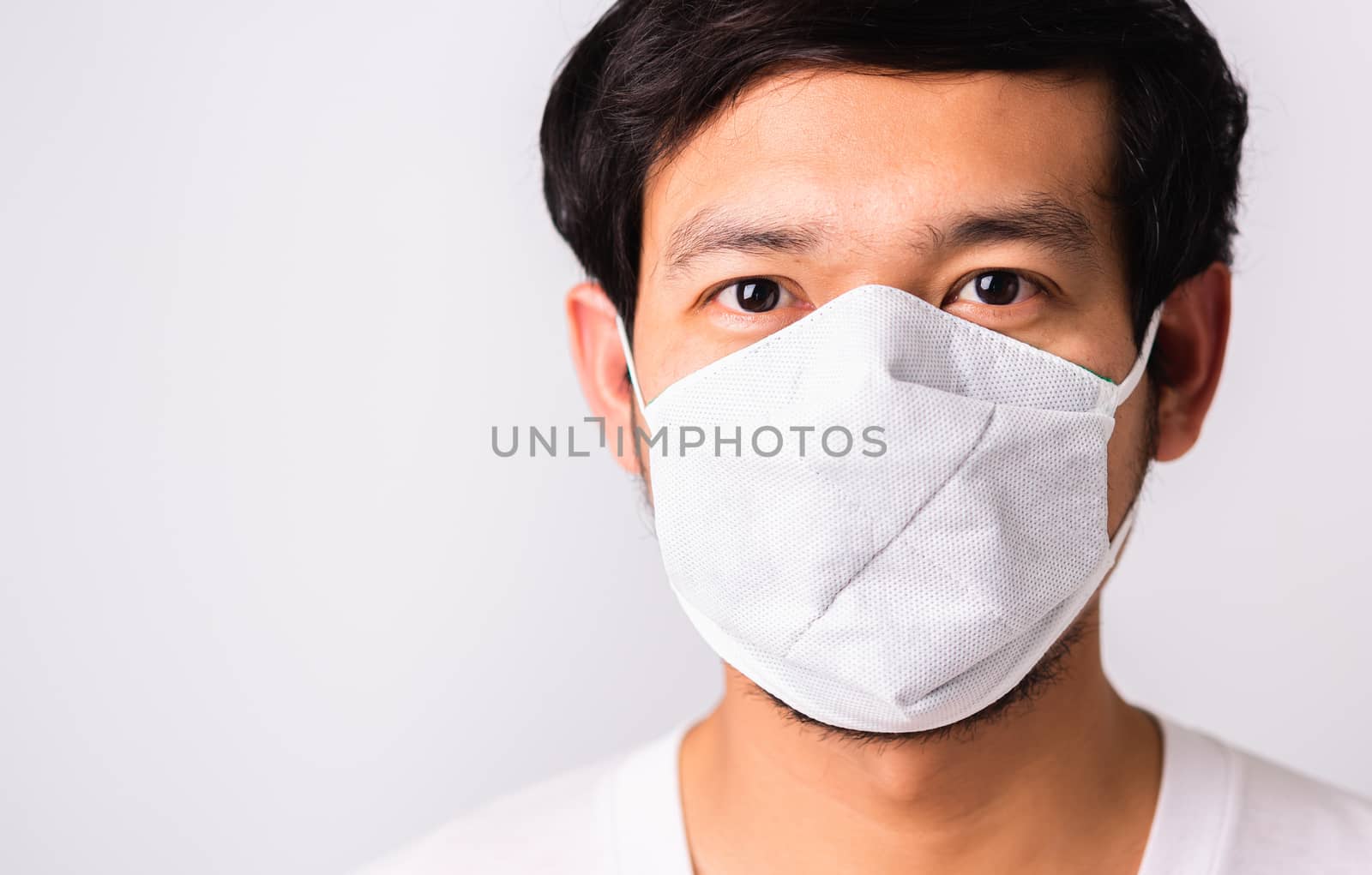 Closeup Asian handsome Man wearing surgical hygienic protective cloth face mask against coronavirus, studio shot isolated white background, COVID-19 medical concept