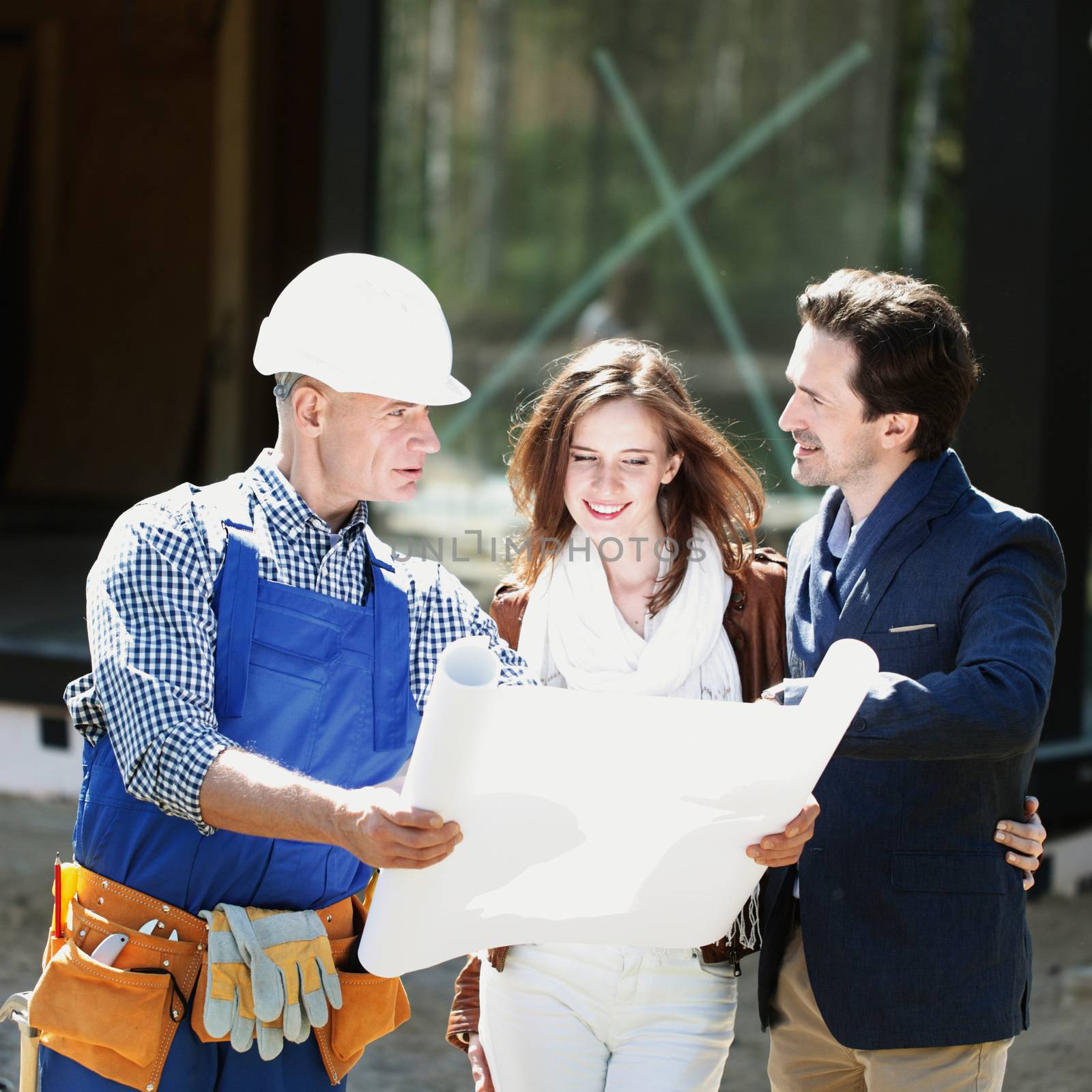 Foreman showing house design construction plan to a happy young couple new house real estate concept