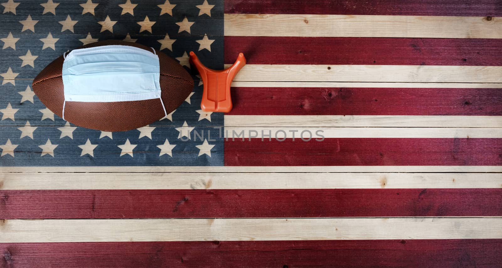 American football with surgical protective mask and kicking tee on vintage United States wooden flag background. Coronavirus concept for affect football sports with copy space