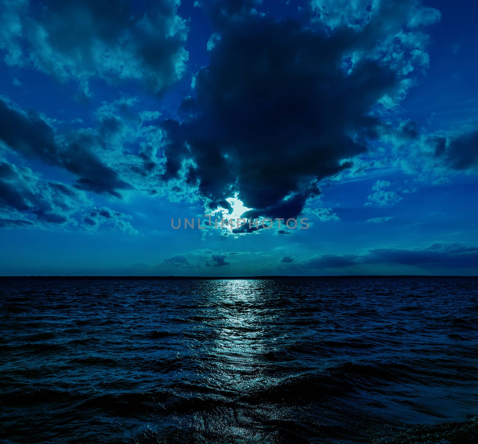 This photo illustration of a deep blue moonlit ocean at night with calm waves would make a great travel background for any coastal region or vacation. by bhavik_jagani