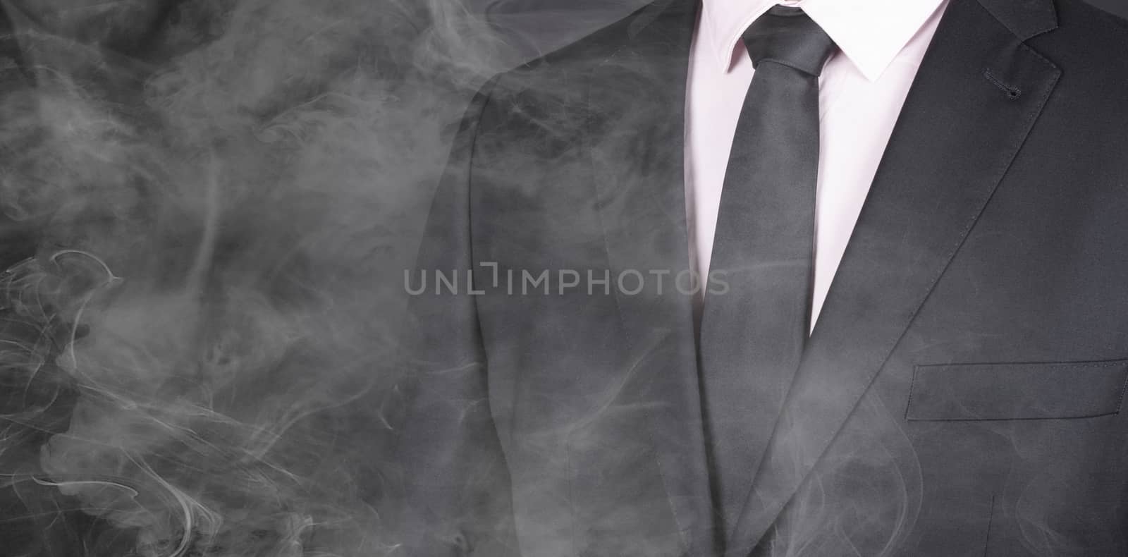 Man in a black suit and black tie, standing in smoke, close-up