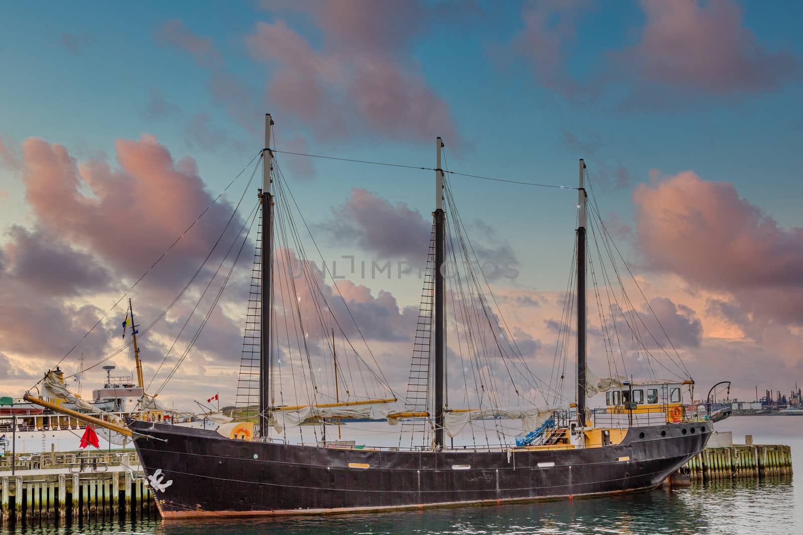 A black three-masted ship in a harbor in Halifax, Nova Scotia