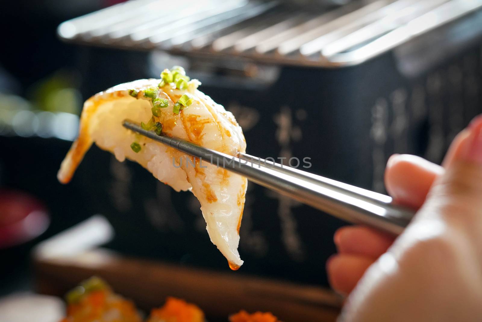 Aburi Engawa Sushi (Fluke fin), Gourmet seafood is clamped with metal chopsticks. Japanese Cuisine Buffet.