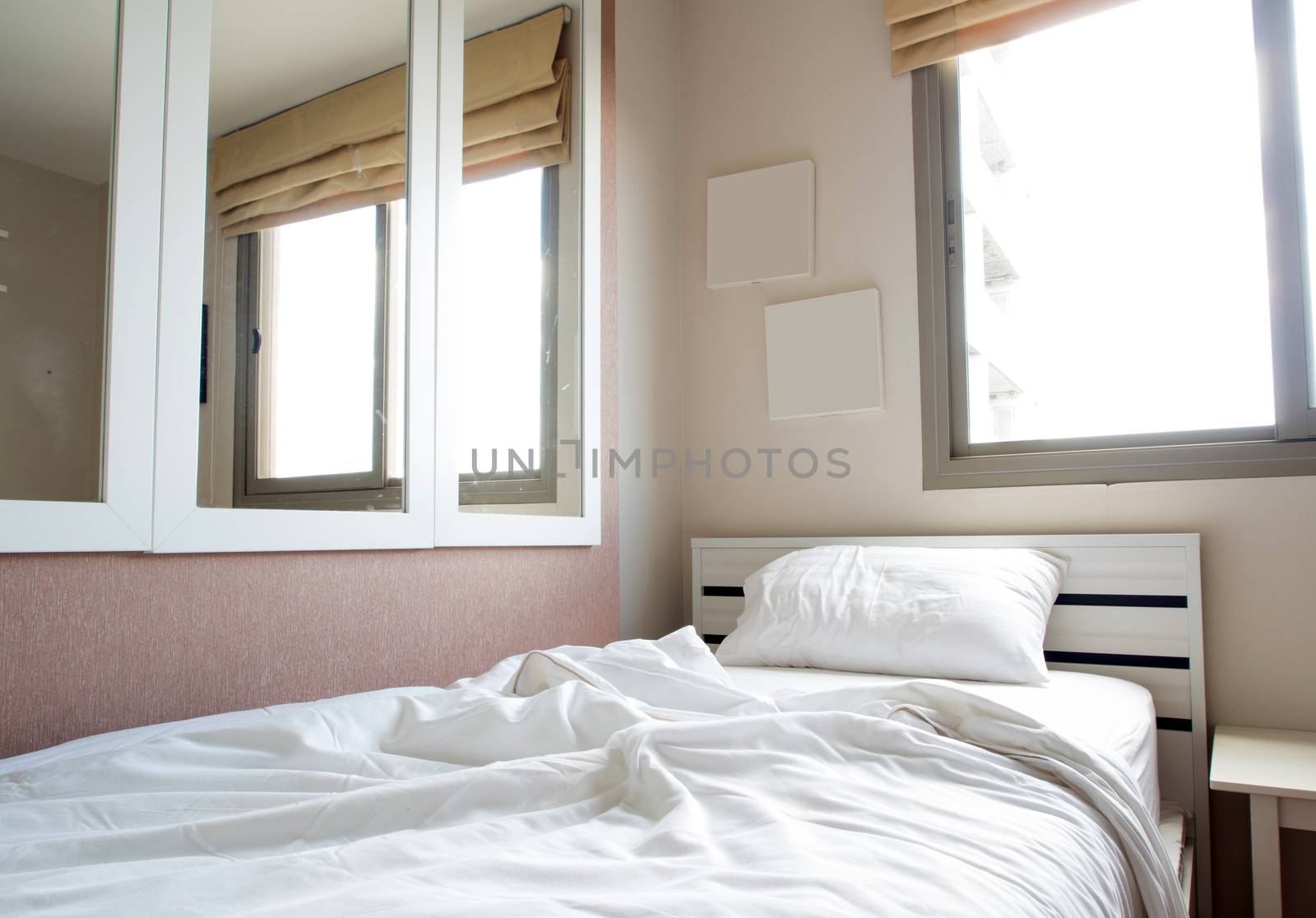 White blanket and pillow on bed in bedroom by Satakorn