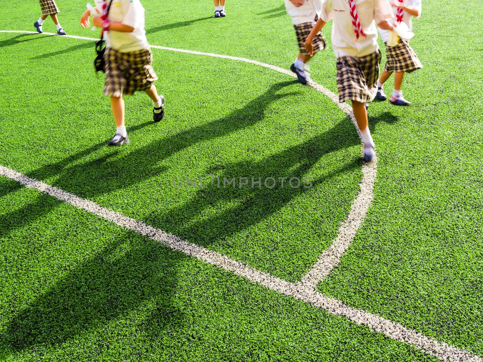 Children play on the artificial turf of the school by Satakorn