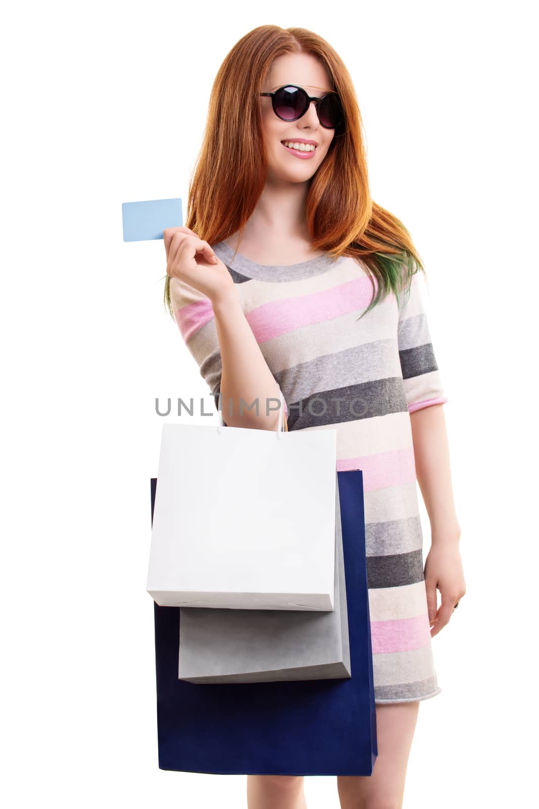 Portrait of a beautiful young girl in a dress with sunglasses, holing shopping bags and a blank card, isolated on white background. Shopping concept, copy space.