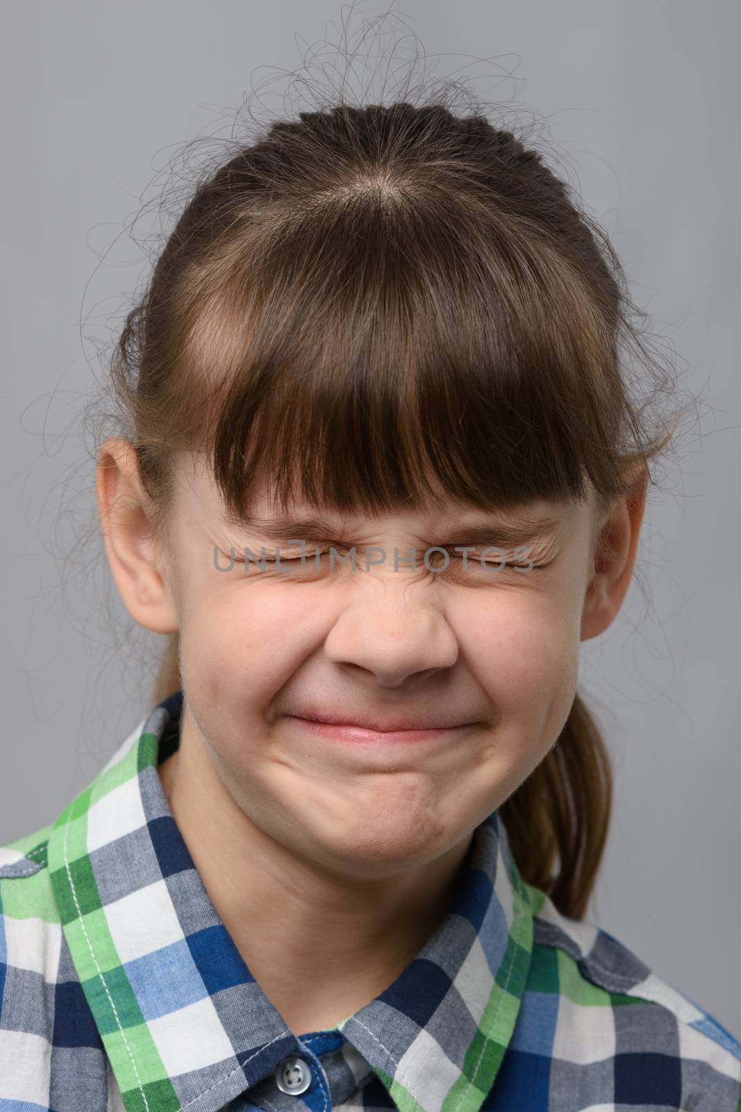 Portrait of a ten-year-old girl squinting her eyes, European appearance, close-up