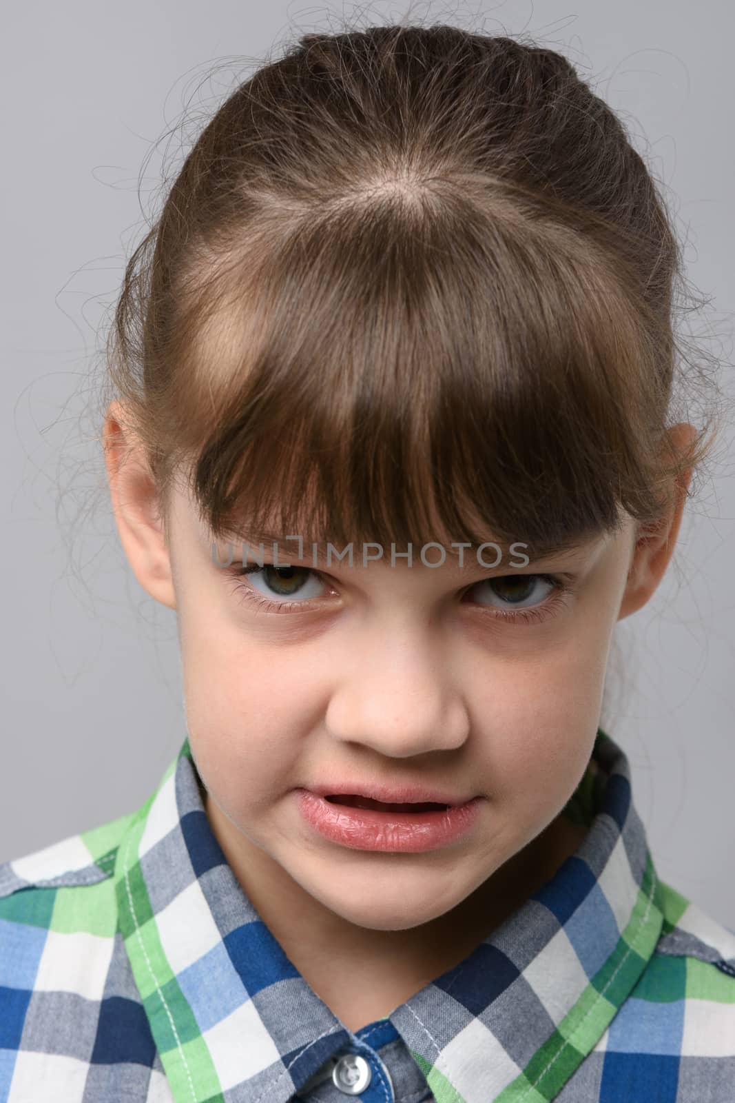 Portrait of an angry grin ten-year-old girl of European appearance, close-up