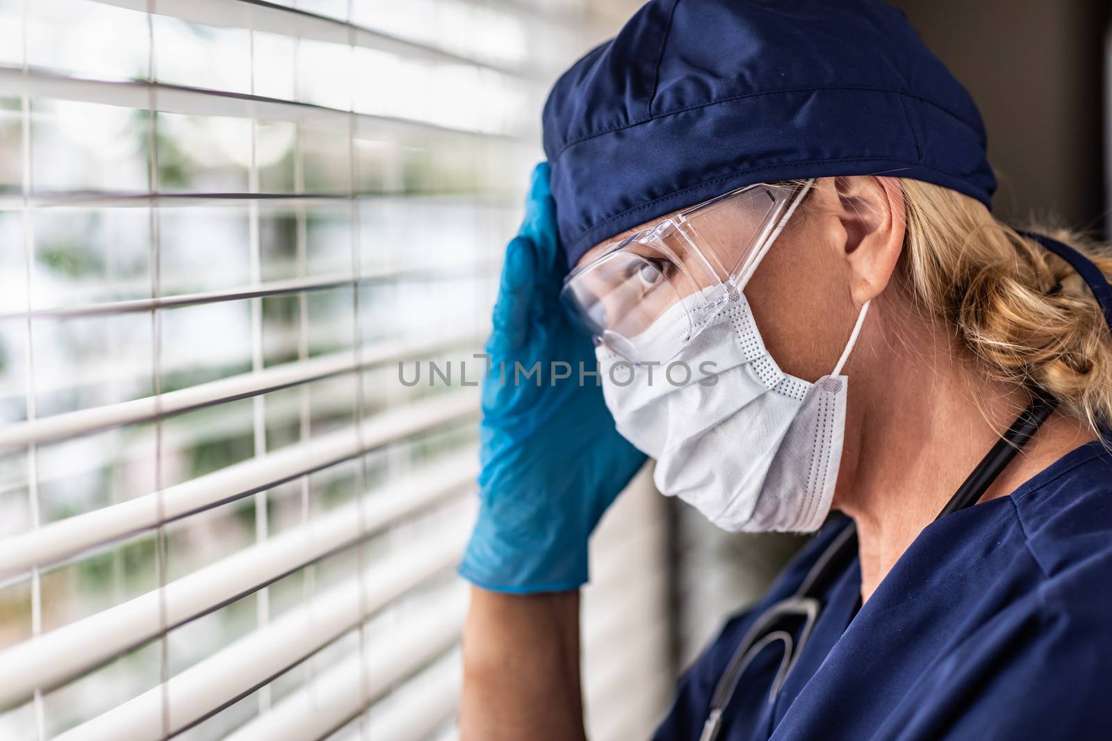 Female Doctor or Nurse On Break At Window Wearing Medical Face Mask and Goggles. by Feverpitched