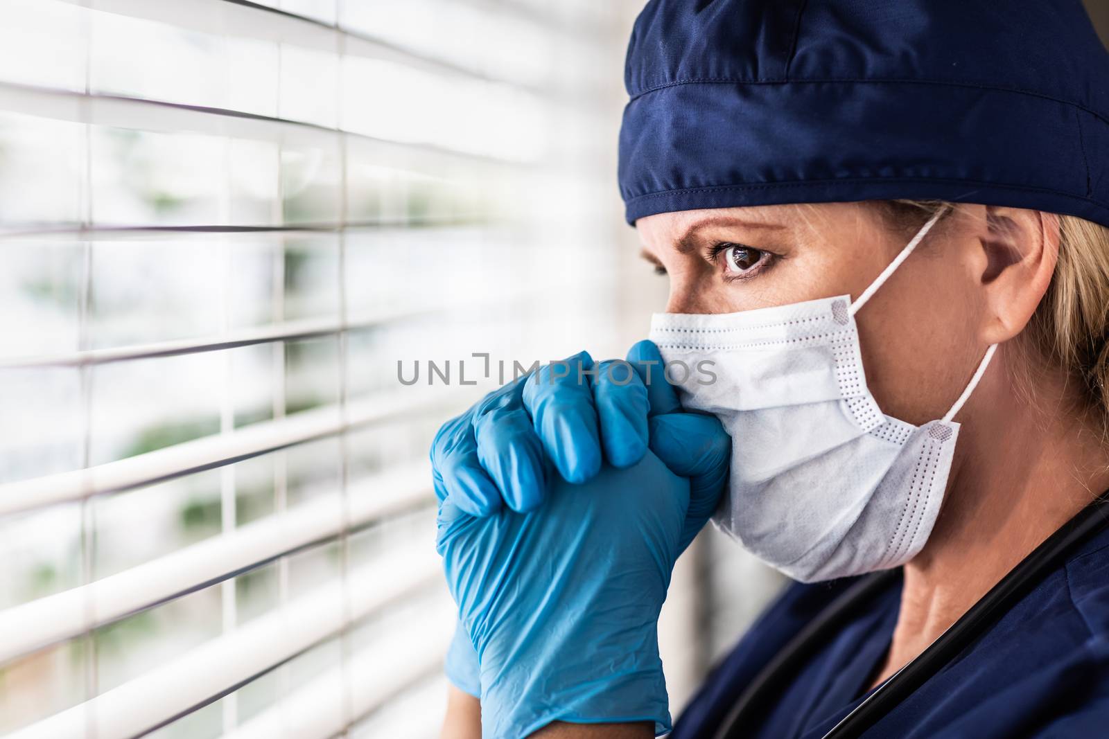 Stressed Female Doctor or Nurse On Break At Window Wearing Medical Face Mask.