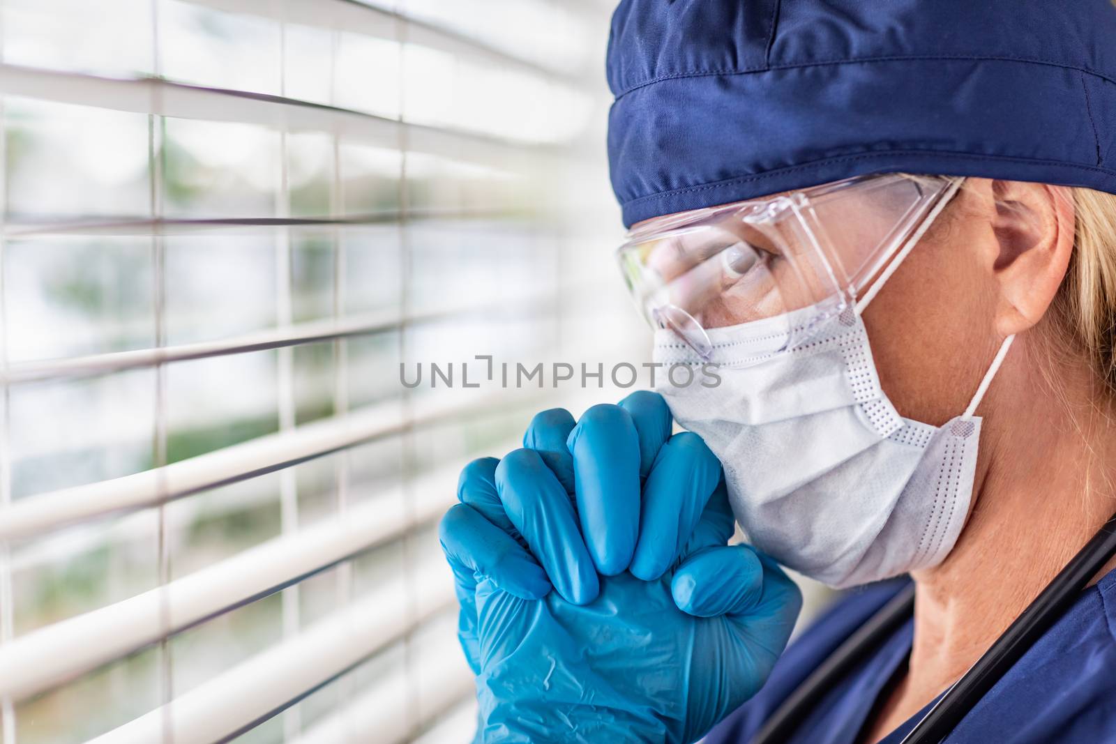 Stressed Female Doctor or Nurse On Break At Window Wearing Medical Face Mask and Goggles. by Feverpitched