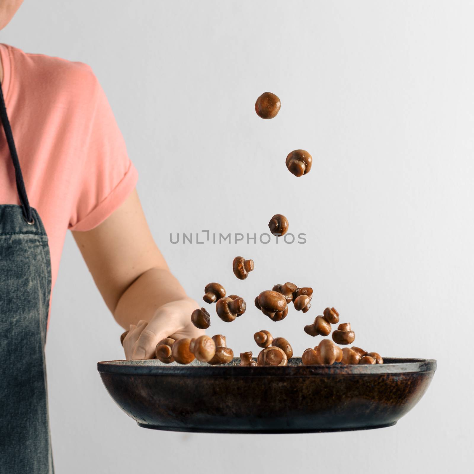 Flying champignons over skillet in hand by fascinadora