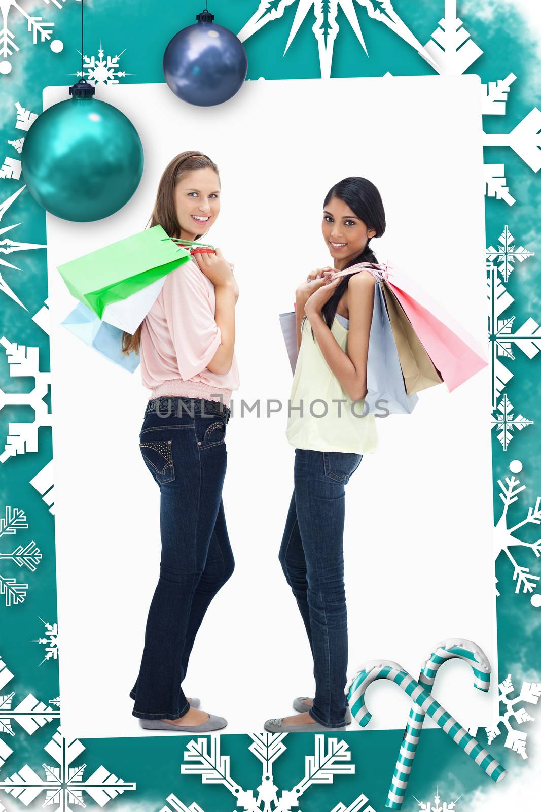 Smiling women carrying a lot of shopping bags against christmas frame