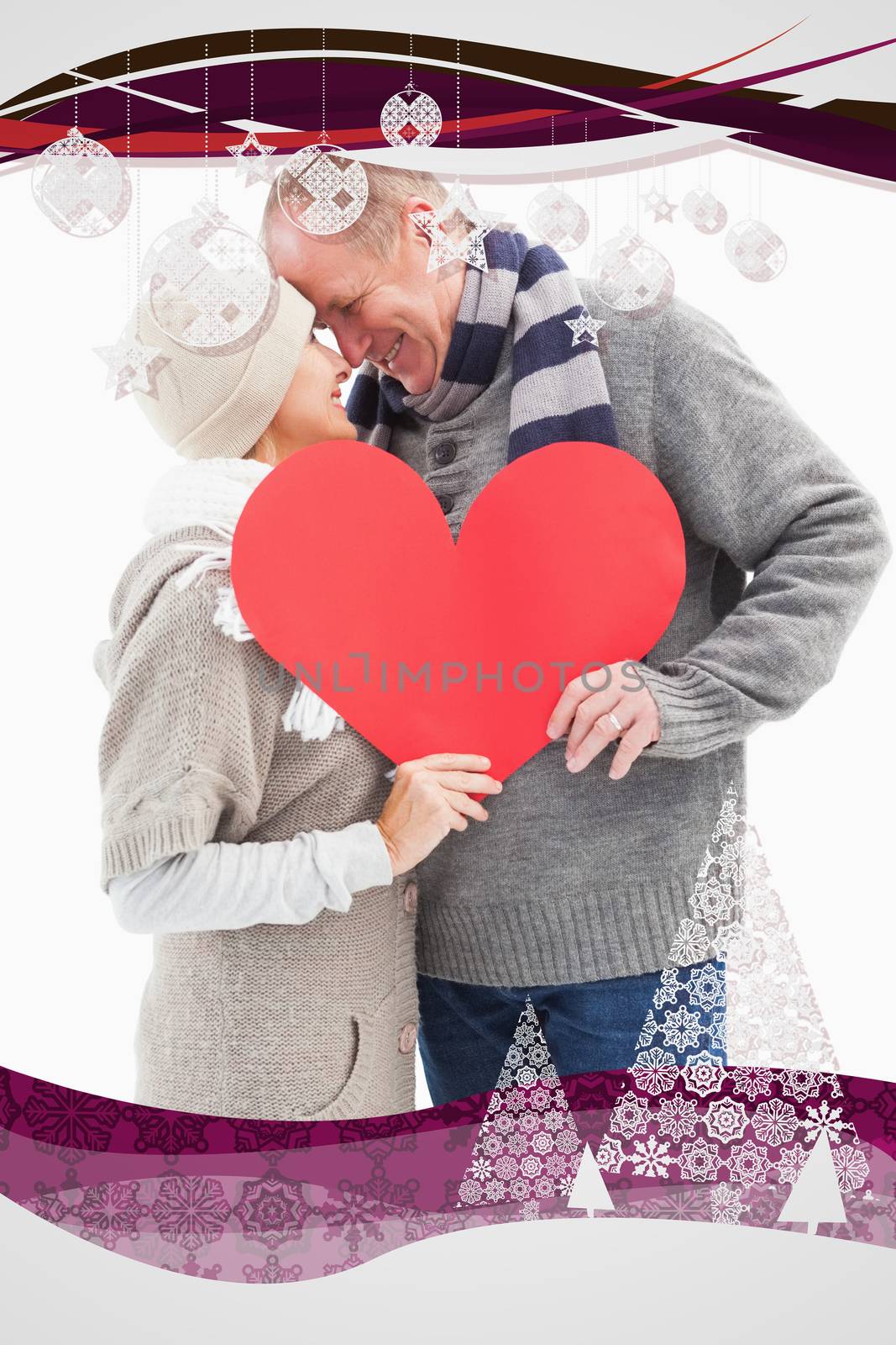 Composite image of happy mature couple in winter clothes holding red heart by Wavebreakmedia